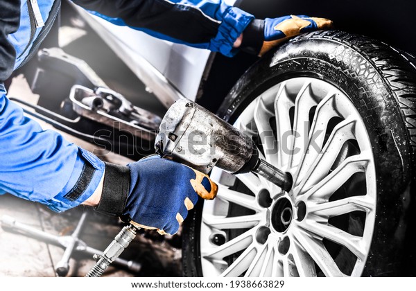 Man mechanic with car tire in service center.\
Changing tire maintenance\
detail.