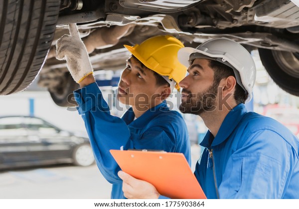 A man mechanic look at engine light. service car\
in garage is paper checklist car. service car, repair, maintenance\
concept.Technician doing the checklist for repair machine a car in\
the garage.