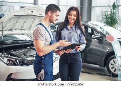 A Man Mechanic And Woman Customer Discussing Repairs Done To Her Vehicle.