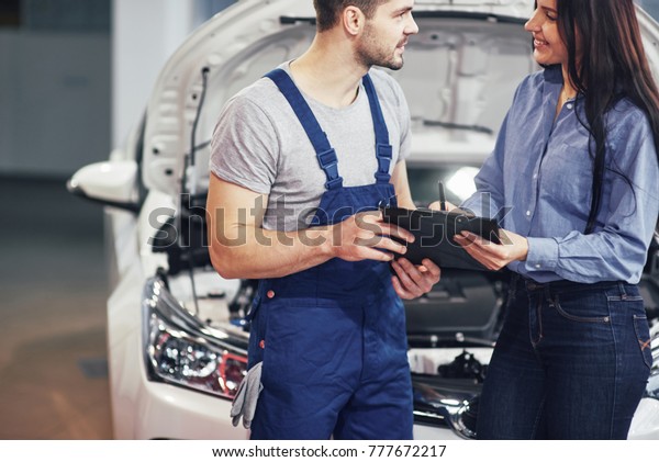 A man mechanic and woman customer discussing\
repairs done to her vehicle.