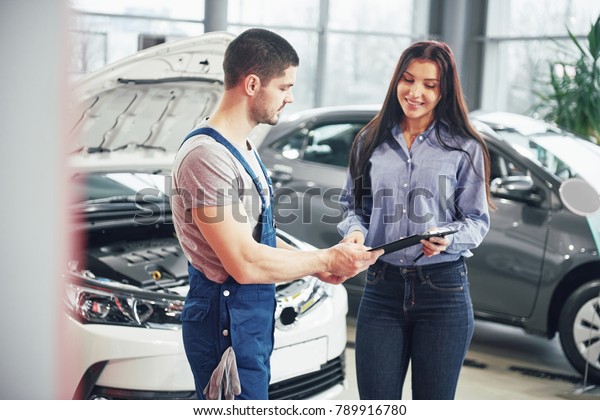 A man mechanic and woman customer discussing\
repairs done to her vehicle.
