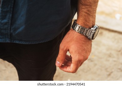 a man with a mechanical watch on his hand. guy in a blue t-shirt with a watch on his wrist. iron strap on men's watch - Powered by Shutterstock