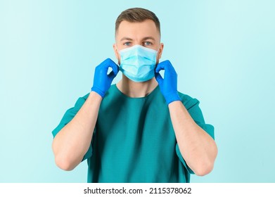 Man in medical gloves putting on protective face mask against blue background