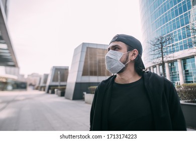 A man in a medical mask on an industrial background of skyscrapers. Lonely young guy in a mask in an empty metropolis. Man and huge city in quarantine. - Shutterstock ID 1713174223