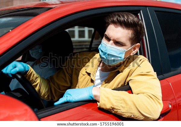 man in medical mask and protective\
gloves driving taxi during coronavirus\
pandemic