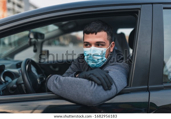 Man\
in the medical mask and rubber gloves for protect himself from\
bacteria and virus while driving a car. masked man in a car.\
coronavirus, disease, infection, quarantine,\
covid-19