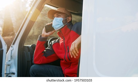 Man With Medical Mask Sitting On The Drivers Seat Of The Van And Having A Phone Call. High Quality Photo