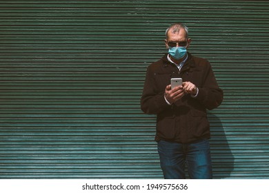 Man With Medical Mask Using Phone In New Normal With Green Blind Background