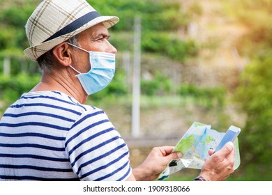 Man In Medical Mask With A World Map In His Hand And In The Other The Mobile Phone, Concept Of Travel In The New Normal