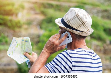 Man In Medical Mask With A World Map In His Hand And In The Other The Mobile Phone, Concept Of Travel In The New Normal