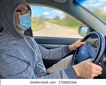 Man in medical protective mask driving car, close-up. Hygienic mask to prevent infection, airborne respiratory illness such as flu, Covid - 2019. Protection against coronavirus, contagious disease.