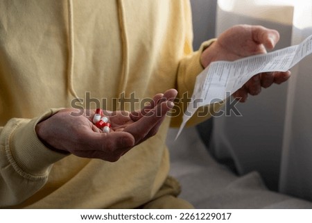 Man with medications reads the instructions for the medical use of the drug.