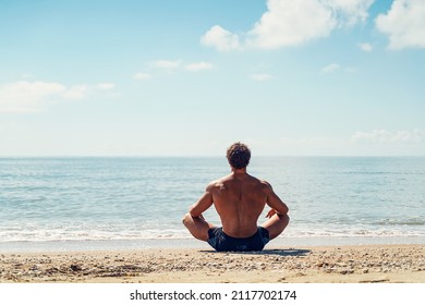 Man Meditates On The Sandy Beach View From The Back.