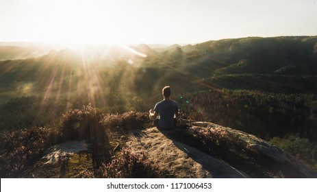 Man meditating in on rocky cliff. Sportsman practicing Yoga on stone edge above landscape, Europe (Saechsische Schweiz) - Powered by Shutterstock