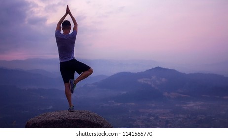 a man meditating and practicing yoga tree pose on a hill top, awaiting for sunrise, with mountains as background. concept of Zen, tranquil, peace and serene - Shutterstock ID 1141566770