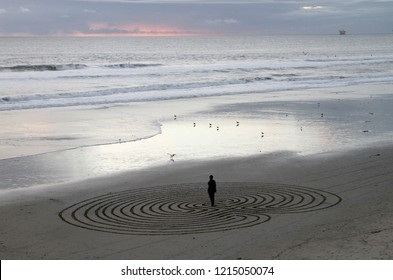 Man meditating in reiki labyrinth maze on beach at sunset - Shutterstock ID 1215050074