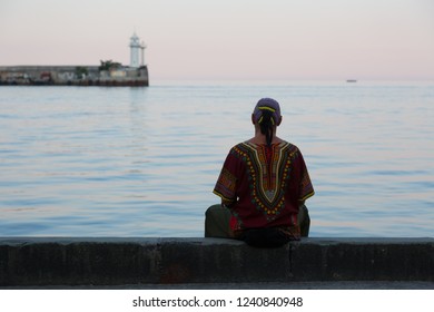Man is meditating while sitting by the sea.