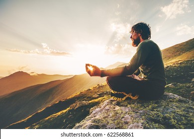 Man meditating yoga lotus pose at sunset mountains Travel Lifestyle relaxation emotional concept summer vacations outdoor harmony with nature calm scene