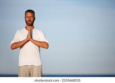 Man, meditation and blue sky with yoga at ocean for mindfulness healing, spiritual peace and performance. Mature person, zen and namaste with chakra for mental health, mindset balance and nature aura - Powered by Shutterstock