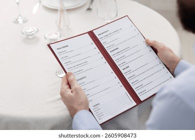 Man with menu at table in restaurant, closeup