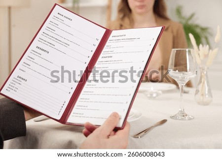 Man with menu at table in restaurant, closeup