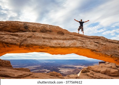 Man at the Mesa Arch at sunrise in the Canyonlands National Park