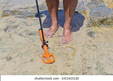 A Man With Metal Detector In Action Is Looking For Lost Jewelry Treasure Under Water In The Sandy Bottom