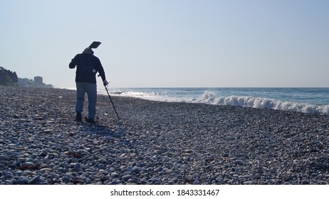 A Man With A Metal Detector Is Looking For Lost Jewelry On The Beach.