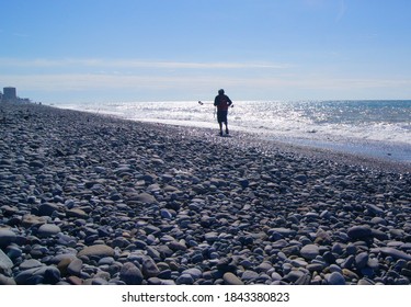 A Man With A Metal Detector Is Looking For Lost Jewelry On The Beach.