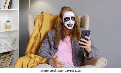 A man a metal head. Male rock musician uses mobile phone and chatting. Web camera. Paint face. Heavy metl. Strange man. Scary face. - Shutterstock ID 1398633128