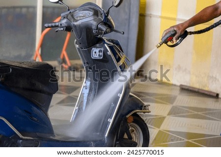 A man methodically cleans his motorcycle with a high-pressure washer