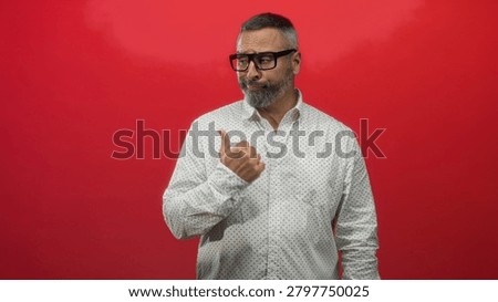 Man middle aged hispanic with grey hair and beard pointing thumb to side wearing white patterned shirt in red studio; wry doubt.