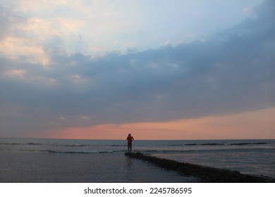 A man in the middle of beach standing while watching sunset