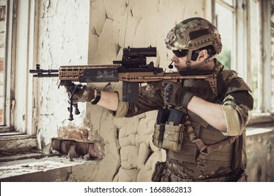 Mann in militärischen Tarnung vegetato Uniform mit automatischen Angriffsgewehr schießt aus dem Fenster in dem alten zerstörten Gebäude