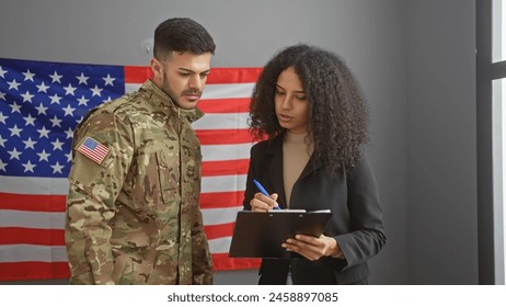 A man in military uniform and a businesswoman with a clipboard confer in front of an american flag in an office. - Powered by Shutterstock