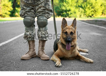 Man in military uniform with German shepherd dog outdoors, closeup