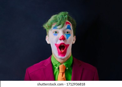 Man In Mime Makeup Cosplay With Green Hair And A Red Suit An Orange Tie And A Green Shirt. Clown Surprised Or Shocked