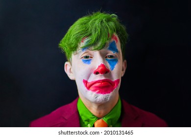 Man in mime makeup cosplay with green hair and a red suit an orange tie and a green shirt. Clown sad - Shutterstock ID 2010131465