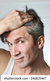 Man With Mirror Looking At His Hair On Gray Background