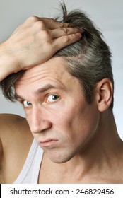 Man With Mirror Looking At His Hair On Gray Background