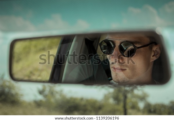 Man in a mirror\
reflection in a car