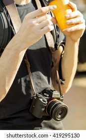 a man with a mirrorless system camera drinking coffee outdoors