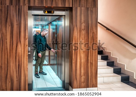 man in modern elevator presses push a button