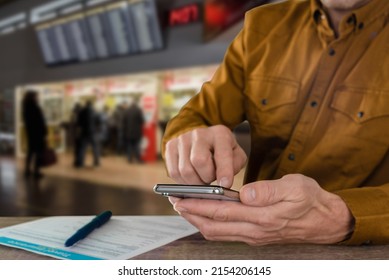 Man With Modern Smartphone Filling Travel Insurance Claim Form In Airport