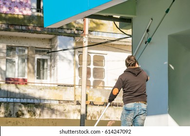 Man with a mop cleans wall