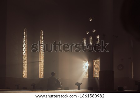 a man in a mosque reads the Qur'an an Arab in a white Kandur Arabic clothing outdoor Qur'an mosque night reading of the Qur'an Ramadan Islam religion Islam