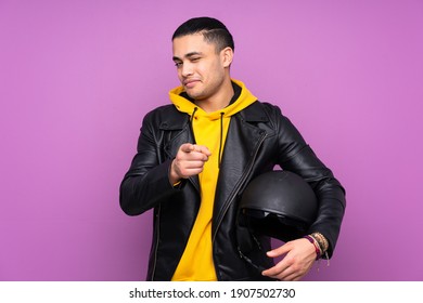 Man With A Motorcycle Helmet Isolated On Purple Background Points Finger At You