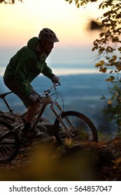 A man mountain biking in the fall at sunset on a single track trail above an escarpment in Ontario, Canada.