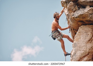 Man mountain or rock climbing while cliff hanging and adrenaline athlete on adventure and check safety equipment, hook and rope. Fearless man doing fitness, exercise and workout during extreme sport