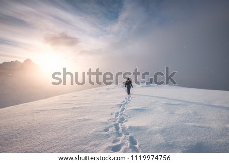 Man mountaineer walking with snow footprint on peak ridge in winter